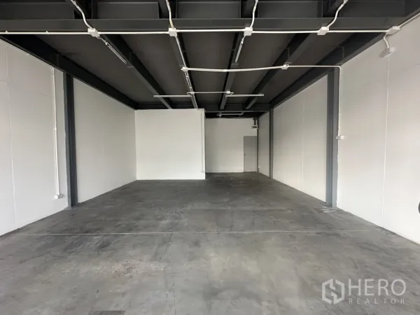 Retail Space for rent - Deep rectangular shop space featuring white walls, durable concrete floor, and surface-mounted lighting conduits.