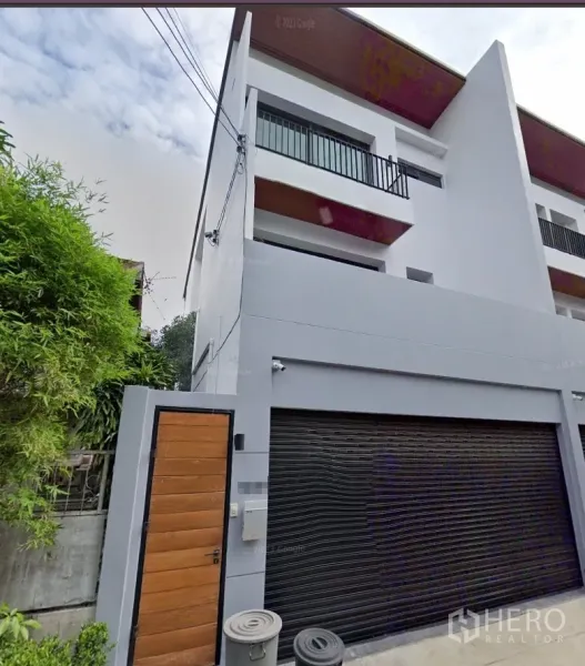 ทาวน์เฮาส์ ให้เช่าในWatthana, Bangkok - หน้าบ้านทาวน์เฮ้าส์สามชั้นสไตล์โมเดิร์น พร้อมประตูโรงรถม้วนสีดำและประตูไม้