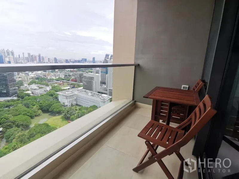 Condominium for rent in Pathum Wan, Bangkok - Private balcony with bistro table and chairs overlooking panoramic city and park views near BTS Chitlom.