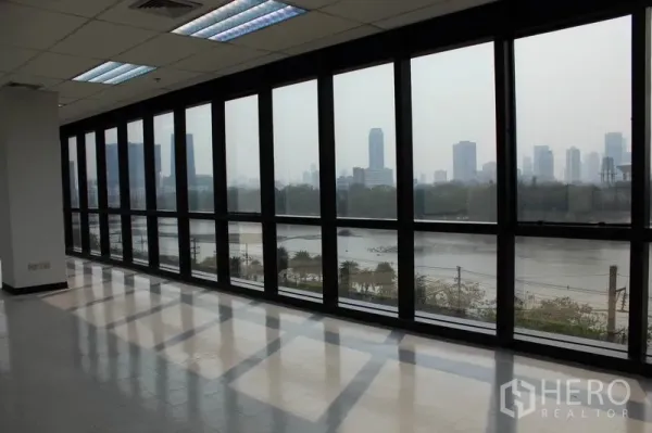 办公空间 出租在Watthana, Bangkok - 一排落地窗，俯瞰湖景与曼谷天际线的全景视野。