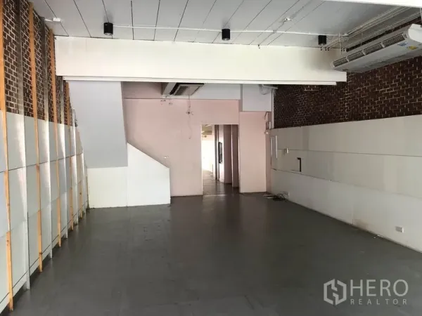 带办公室的家 出租或出售在Huai Khwang, Bangkok - 一层另一角度，砖饰墙、瓷砖地面与通往后区的通道。