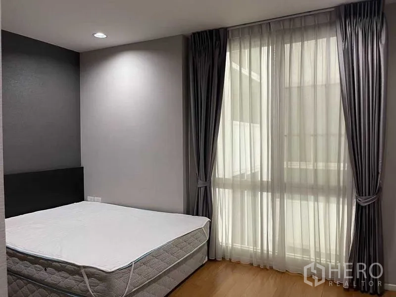 公寓 出租在Watthana, Bangkok - 卧室一角，落地窗帘与大窗引入自然采光。