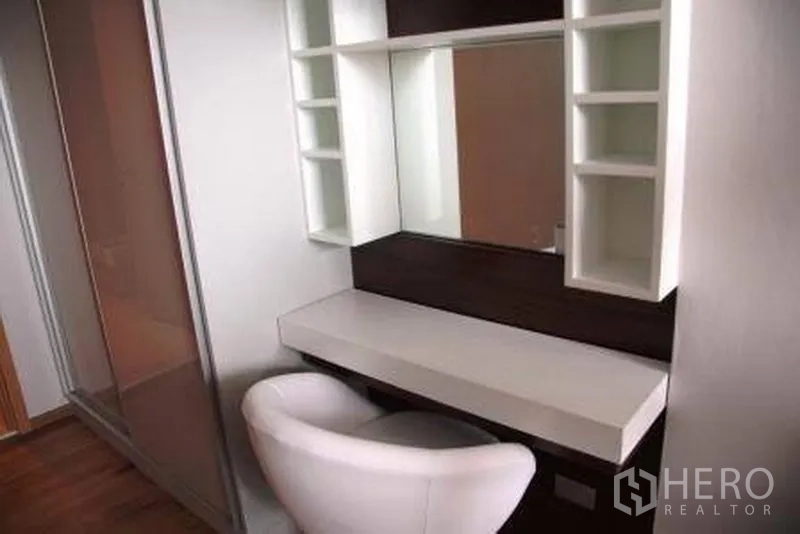 Condominium for rent or sale in Watthana, Bangkok - Built-in dressing table with large mirror, shelving and white chair beside the wardrobe.