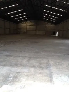 Warehouse for rent in Nakhon Pathom - Spacious warehouse interior with high steel truss roof, skylights, and smooth concrete floor.