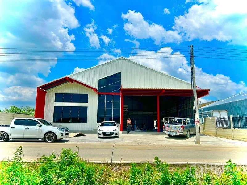 Warehouse for rent in Lam Luk Ka, Pathum Thani - Front facade of the warehouse with tall glass panels and a covered loading bay with parking.