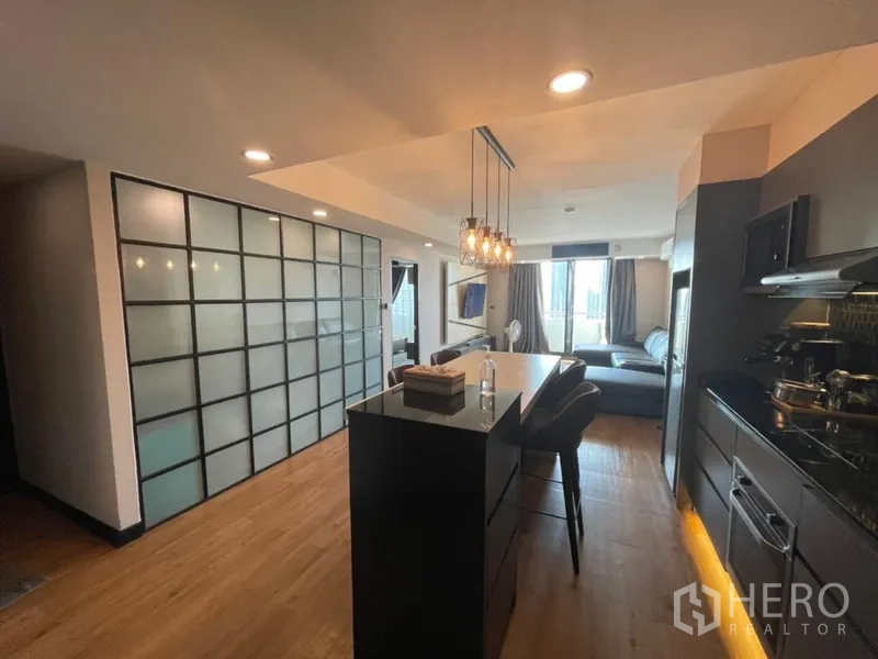 Condominium for sale in Chatuchak, Bangkok - Dining island with pendant lights beside a frosted glass partition leading to a bright living room.