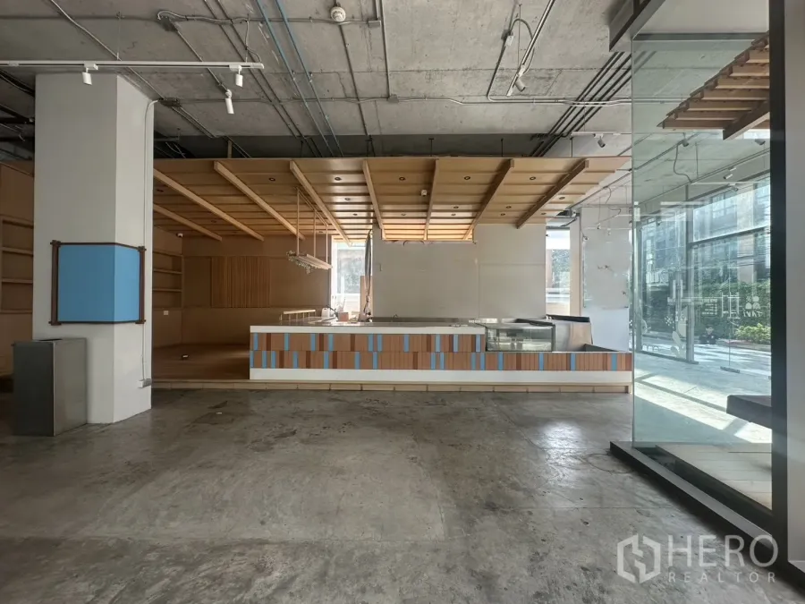 Retail Space for rent - Ground-floor retail interior with wood feature ceiling, service counter, and floor-to-ceiling glass frontage.