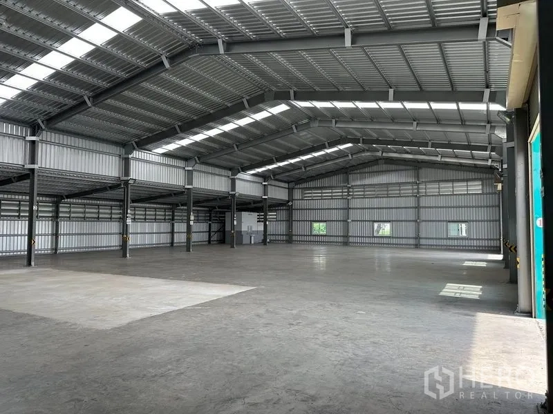 货栈 出租在Mueang Nonthaburi, Nonthaburi - 仓库内部宽敞，高钢结构屋架与采光带，光滑混凝土地面。
