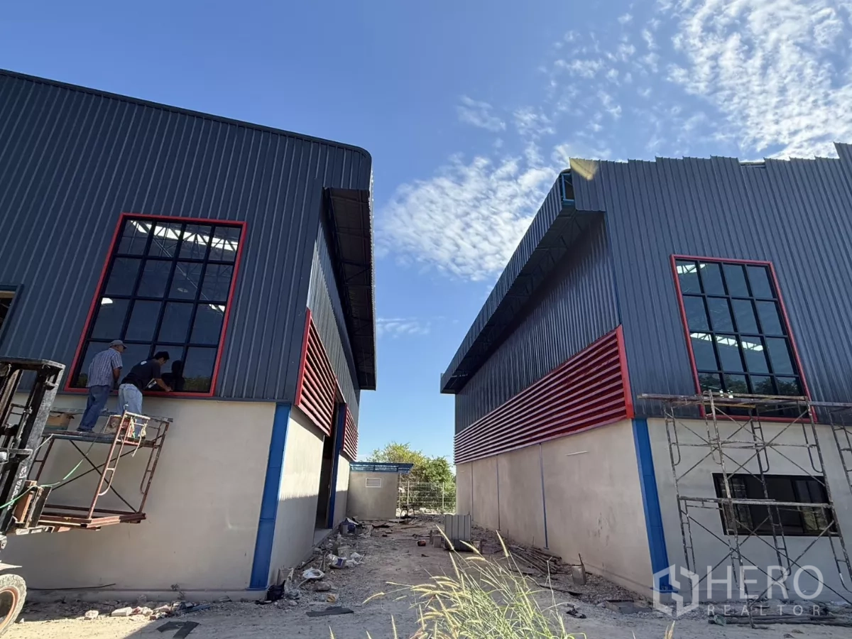 Warehouse for rent in Lam Luk Ka, Pathum Thani - Two adjacent warehouse buildings with tall windows and red ventilation slats.