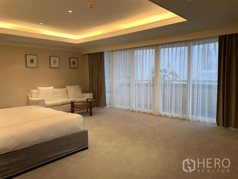公寓 出租或出售在Watthana, Bangkok - 超大卧室，地毯地面，带沙发角与通向阳台的纱帘。
