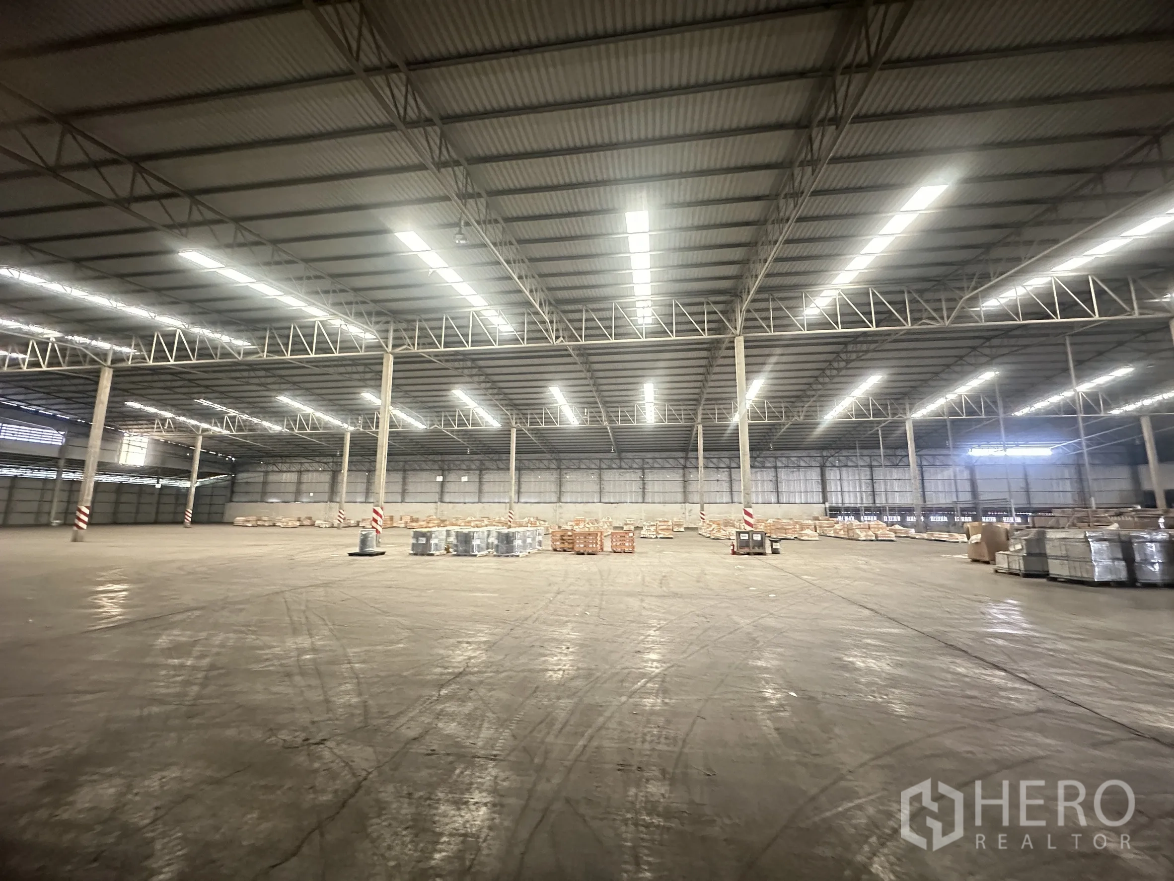 Warehouse for rent in Bang Pa-in, Phra Nakhon Si Ayutthaya - Broad interior span with concrete floor and materials stored on pallets.