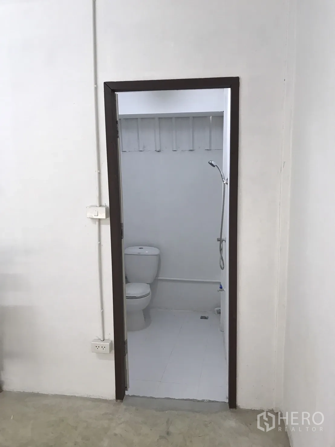 Warehouse for rent in Lam Luk Ka, Pathum Thani - Clean restroom with toilet and handheld shower inside the warehouse.