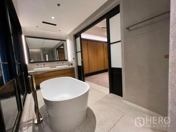 Condominium for rent in Sathon, Bangkok - Spa-like bathroom with a freestanding oval bathtub, double vanity and sliding glass doors.