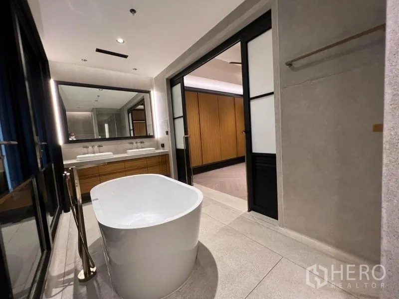 Condominium for rent in Sathon, Bangkok - Spa-like bathroom with a freestanding oval bathtub, double vanity and sliding glass doors.