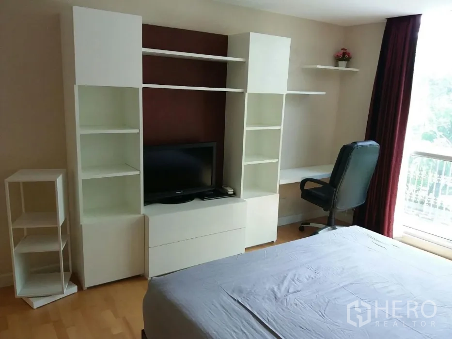 公寓 出租在Phaya Thai, Bangkok - 卧室收纳墙，带开放书架、电视与窗边书桌。