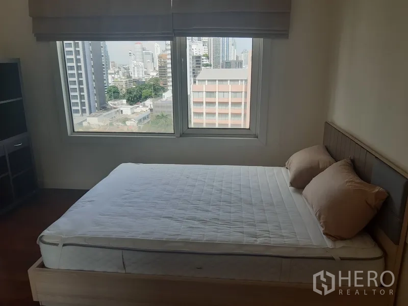 Condominium for rent in Khlong Toei, Bangkok - Second bedroom with bed, big windows, and urban view over nearby buildings.