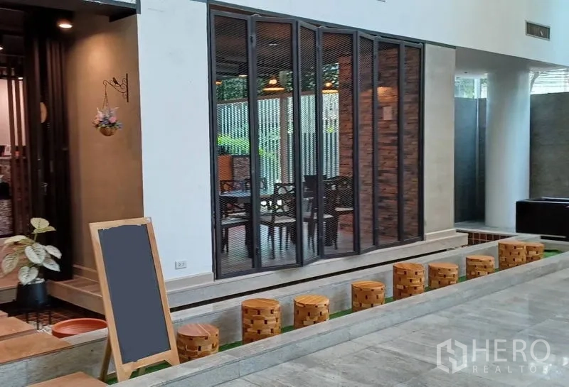 พื้นที่ขายปลีก ให้เช่าในKhlong Toei, Bangkok - หน้าร้านสมัยใหม่ ประตูกระจกพับ ผนังอิฐโชว์ และที่นั่งไม้ริมทางเดินยกพื้น