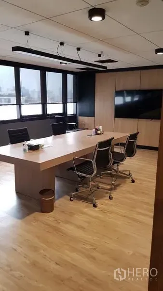 Office Space for rent in Khlong Toei, Bangkok - Boardroom featuring a long wooden table, swivel chairs, ceiling track lights and a wall-mounted TV beside large windows.