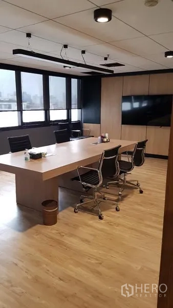 Office Space for rent in Khlong Toei, Bangkok - Boardroom featuring a long wooden table, swivel chairs, ceiling track lights and a wall-mounted TV beside large windows.