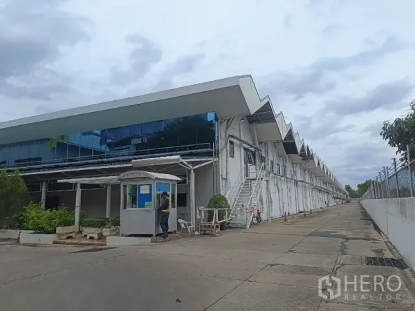 Warehouse for rent in Lam Luk Ka, Pathum Thani - Front office wing with reflective glass, guard booth and side service staircase along the warehouse.