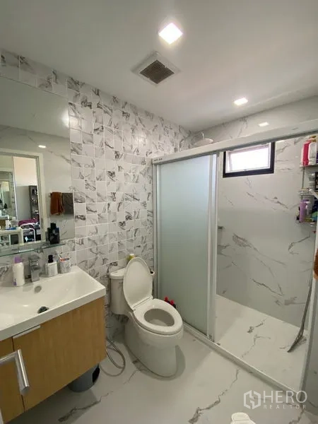 Townhouse for rent in Suan Luang, Bangkok - Modern bathroom with vanity, marble-look tiles and a glass sliding shower enclosure.