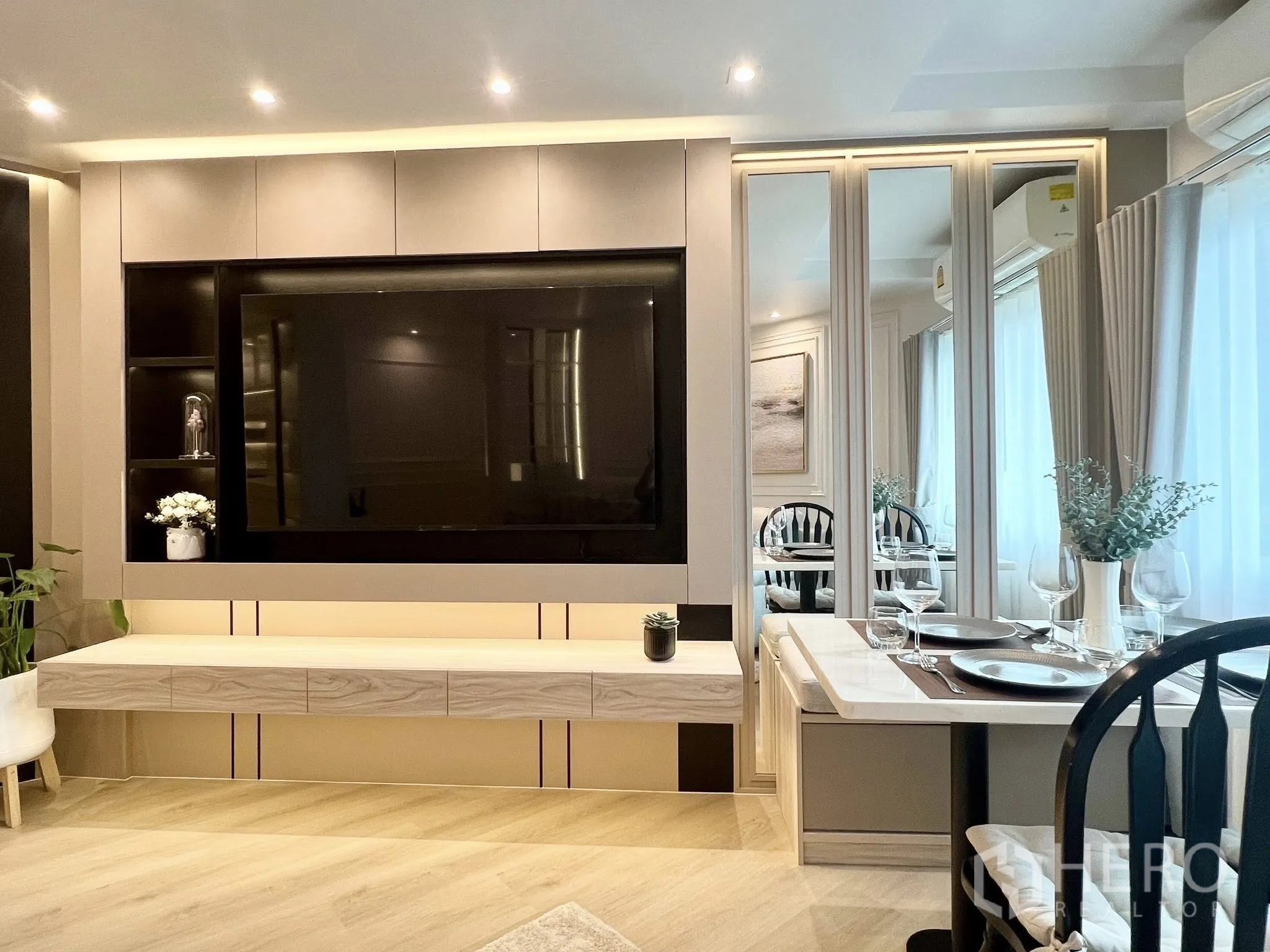公寓 for rent or sale in Yan Nawa, Bangkok - 客厅采用电视背景墙与镜面柜，窗边摆放餐桌。