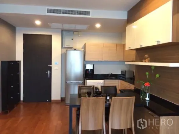 公寓 出租在Pathum Wan, Bangkok - 开放式厨房与餐区，木质橱柜、冰箱和四人餐桌。