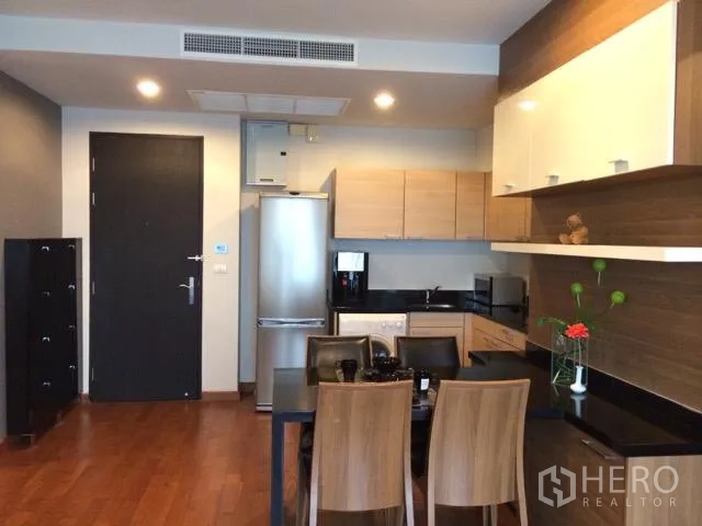 公寓 出租在Pathum Wan, Bangkok - 开放式厨房与餐区，木质橱柜、冰箱和四人餐桌。