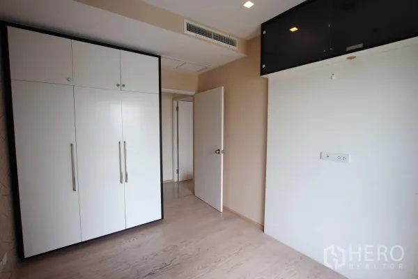 Condominium for rent in Khlong Toei, Bangkok - Second bedroom with light wood flooring, large built-in wardrobe and neutral walls, ready for customization.