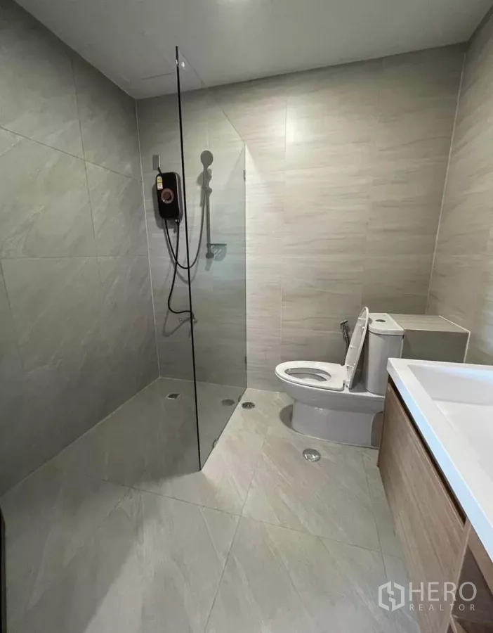Condominium for rent in Sathon, Bangkok - Tiled bathroom with walk-in rain shower and glass divider.