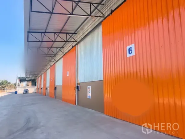货栈 出租在Khlong Luang, Pathum Thani - 编号仓库库门橙色醒目，前方卡车通行与停靠空间充足。