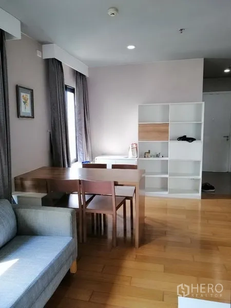 Condominium for rent in Watthana, Bangkok - Open-plan dining area with table and shelving in a sunlit corner