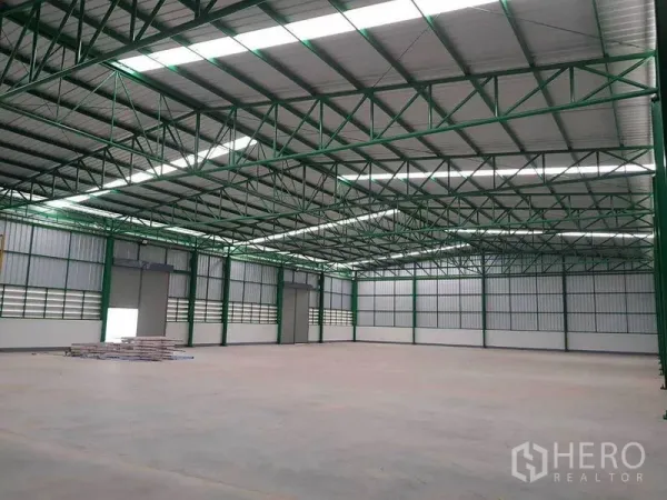 Warehouse for rent in Prawet, Bangkok - Clear-span warehouse interior with high green steel trusses, skylight panels and smooth concrete floor.
