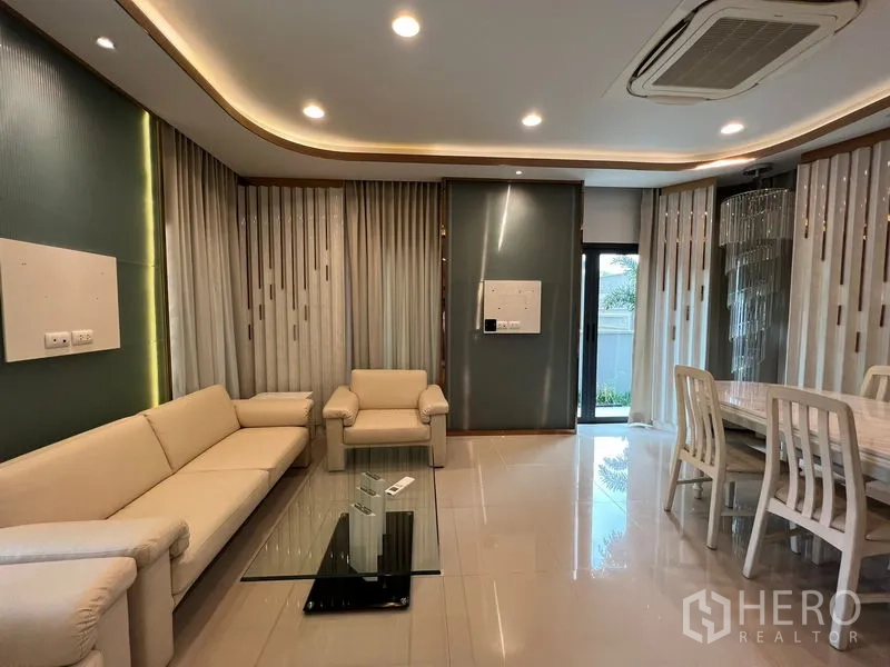 Detached House for rent in Saphan Sung, Bangkok - Open-plan living and dining area with recessed lighting, cream sofa set and a glass coffee table.