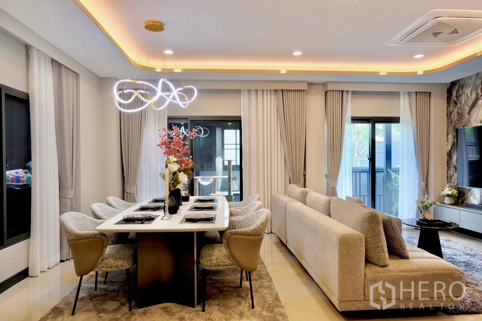 半独立式住宅 for sale in Prawet, Bangkok - 餐桌与客厅一角，带灯带吊顶与石纹电视墙。