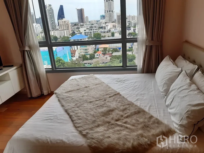 公寓 出租在Watthana, Bangkok - 主卧配大窗城市景观与铺好的床品。
