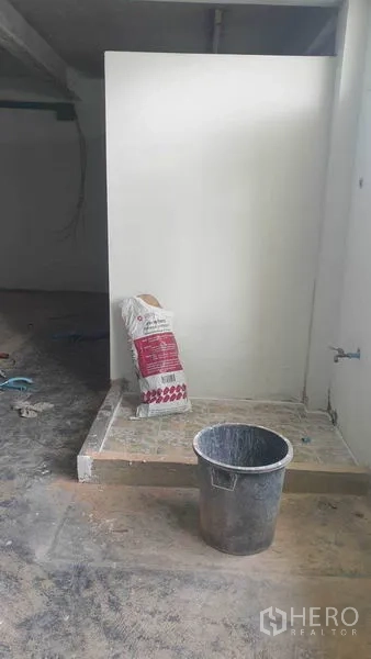 Shophouse for rent in Phra Khanong, Bangkok - Small indoor utility corner under renovation with a bucket and bag of cement.
