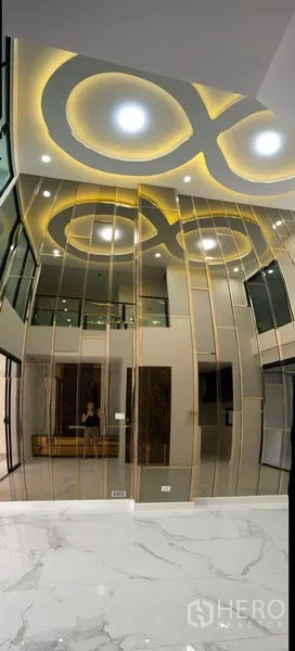 Townhouse for rent or sale in Yan Nawa, Bangkok - Double-height living room featuring a mirrored statement wall and circular recessed ceiling lights.