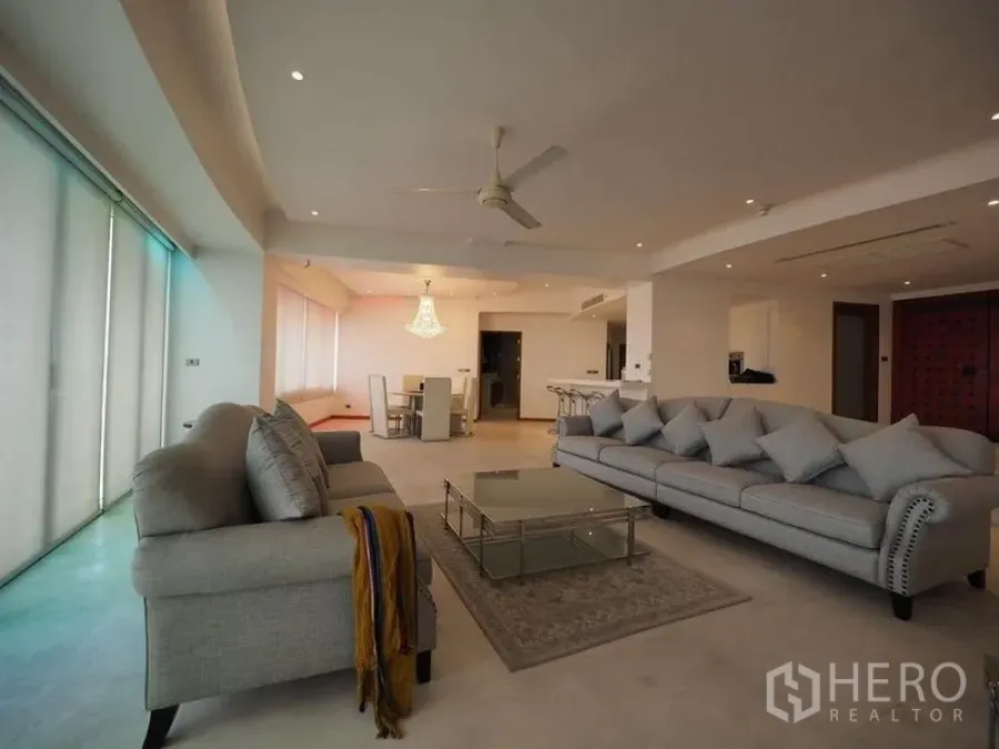 Condominium for rent in Khlong San, Bangkok - Spacious living area with two grey sofas, ceiling fan and glass coffee table.