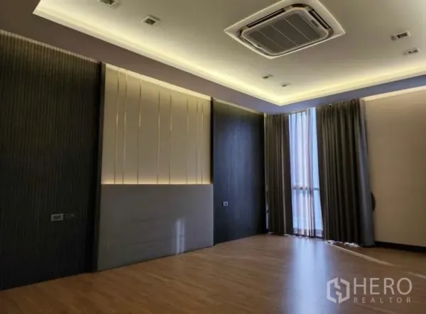 Townhouse for sale in Yan Nawa, Bangkok - Spacious bedroom with cove lighting, cassette AC, wood floors and full-length curtains.