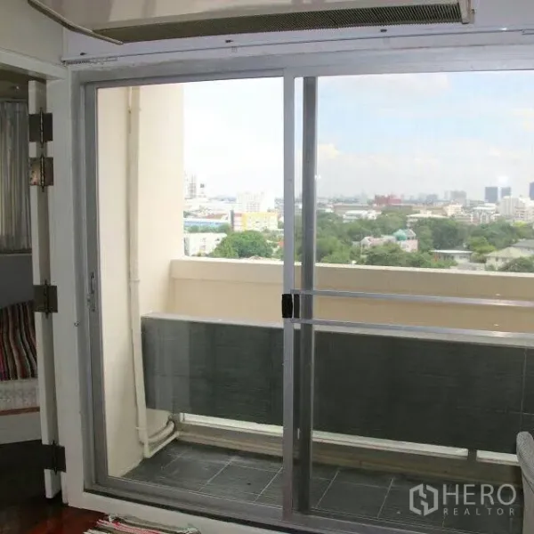 公寓 出租在Watthana, Bangkok - 推拉玻璃门通向阳台，远眺曼谷天际线与绿色景致。