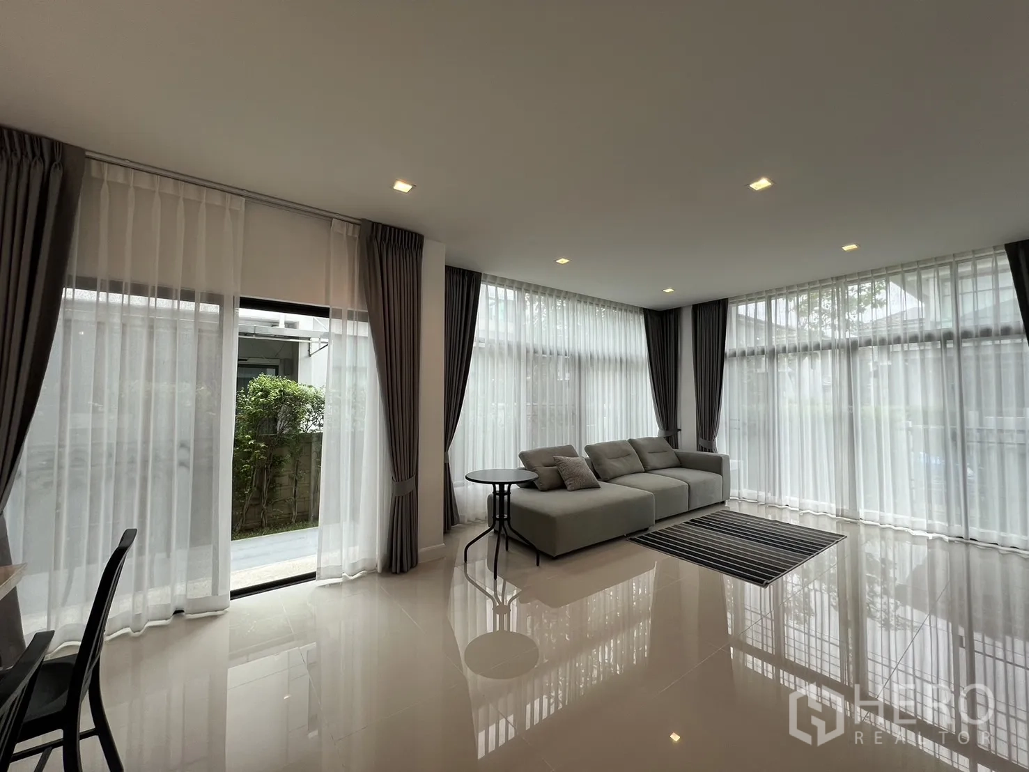 Detached House for rent in Bang Kapi, Bangkok - Lounge with wraparound windows, sheer curtains and access to garden terrace.