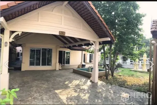 Detached House for sale in Saphan Sung, Bangkok - Covered carport and tiled front patio with sliding glass doors and a small garden area.