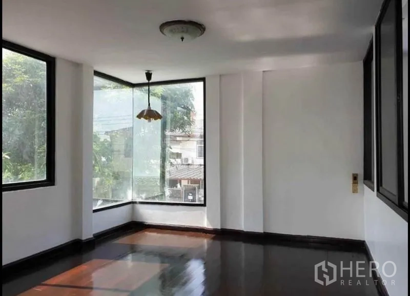 独立式住宅 出租在Lat Phrao, Bangkok - 二层转角房，落地转角窗、吊灯与亮面深色木地板。