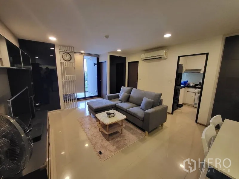 Condominium for rent or sale in Phaya Thai, Bangkok - Living area facing the balcony entrance with separate kitchen and air conditioning.