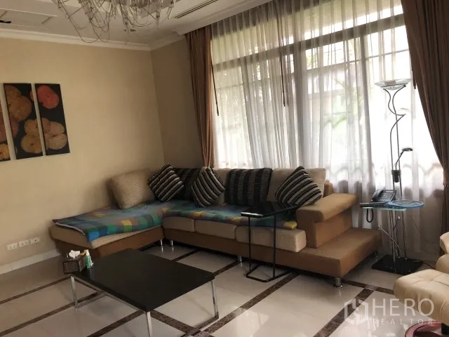 Detached House for rent in Bang Phli, Samut Prakan - Bright living room featuring an L-shaped sofa, large window and chandelier on tiled floors.
