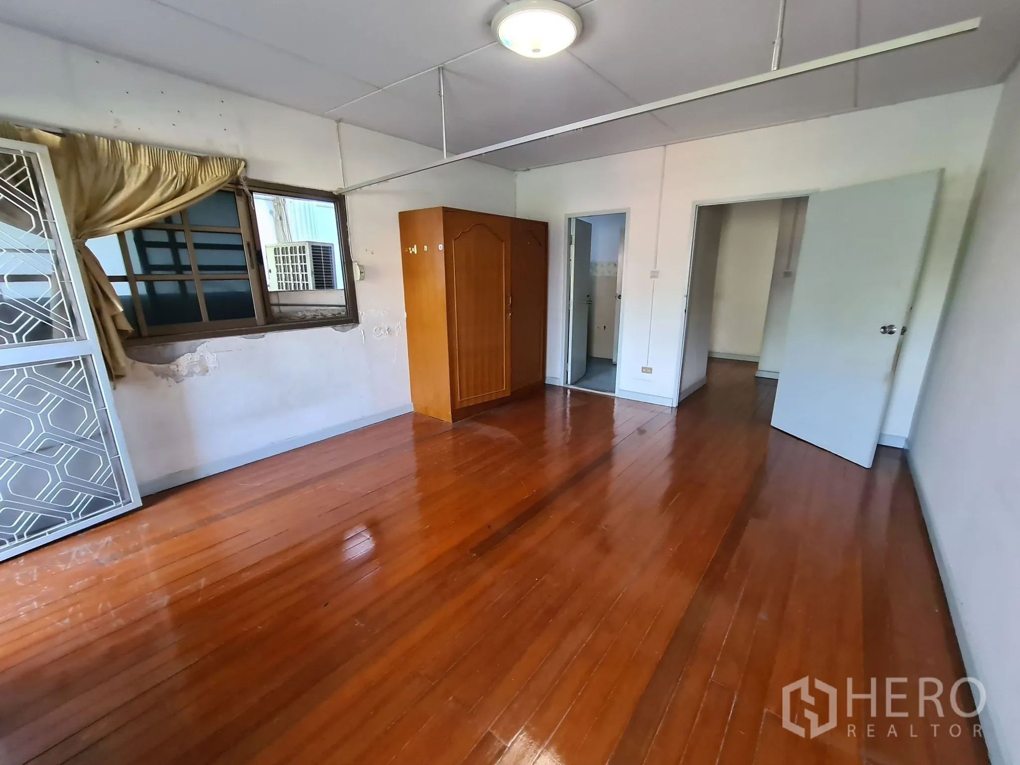 Detached House for sale in Chatuchak, Bangkok - Secondary house bedroom with polished wood floors and windows.