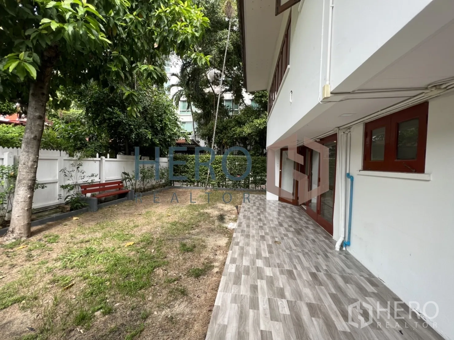 独立式住宅 出租在Watthana, Bangkok - 侧边露台铺灰砖，邻草坪与白色围栏