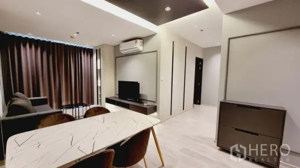 公寓 出售在Watthana, Bangkok - 现代客餐厅，带大理石桌、沙发、电视柜和深色窗帘。