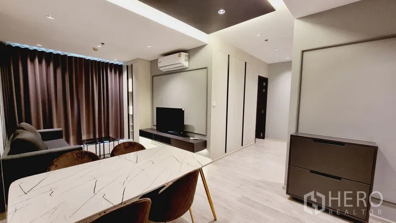 公寓 出售在Watthana, Bangkok - 现代客餐厅，带大理石桌、沙发、电视柜和深色窗帘。